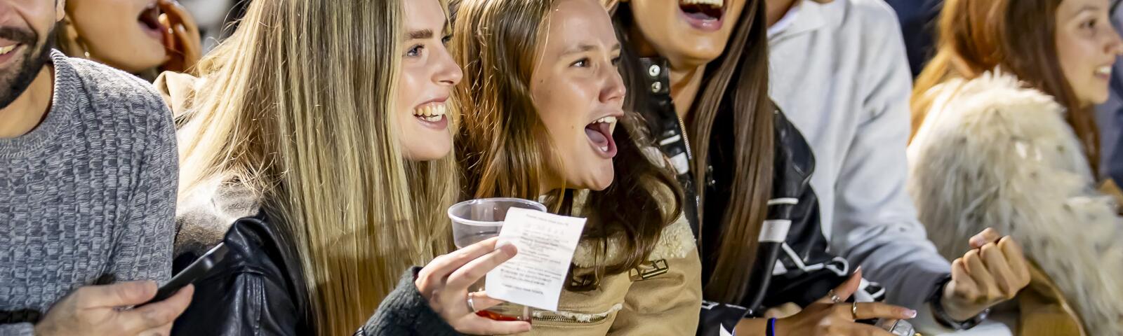Racegoers at Wolverhampton cheer and hold on their betting slips as they watch the race