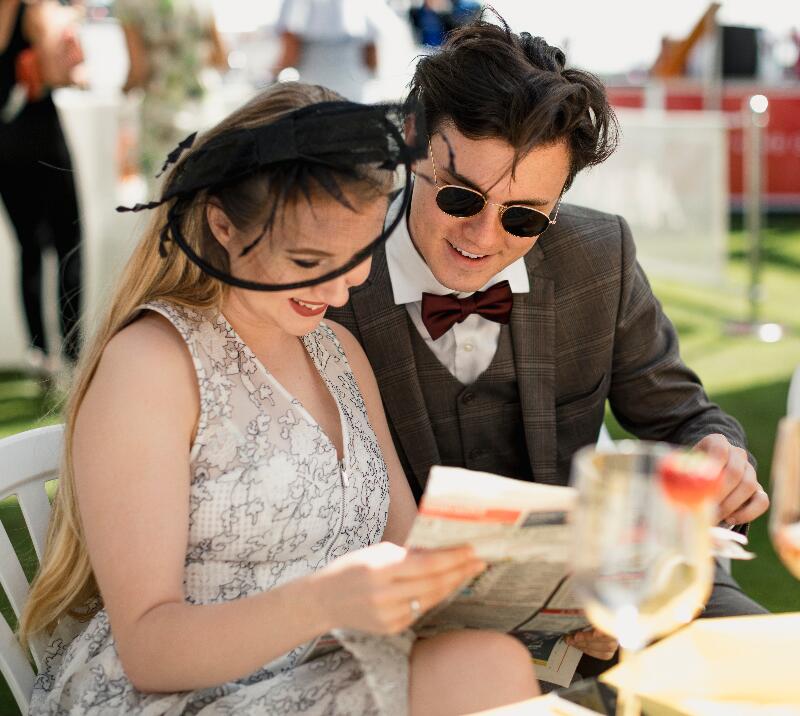 A couple reading a racing paper.