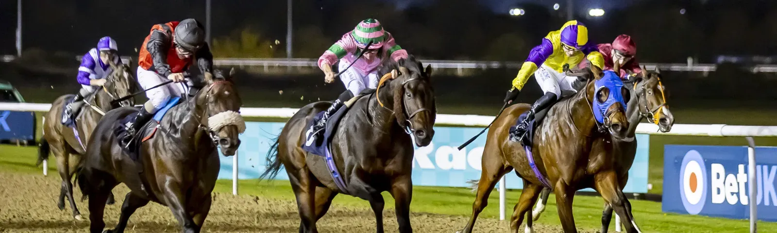 Horses race towards the finish under the floodlights at Wolverhampton Racecourse