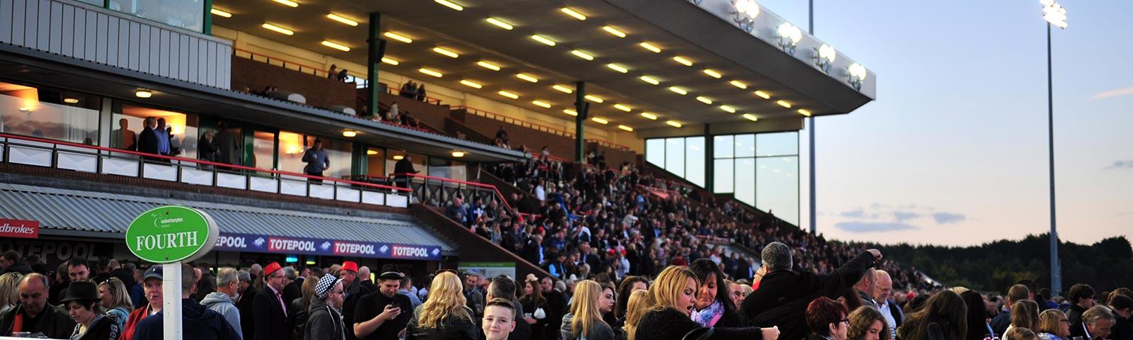 Crowds watching racing from the grandstand at Wolverhampton Racecourse.