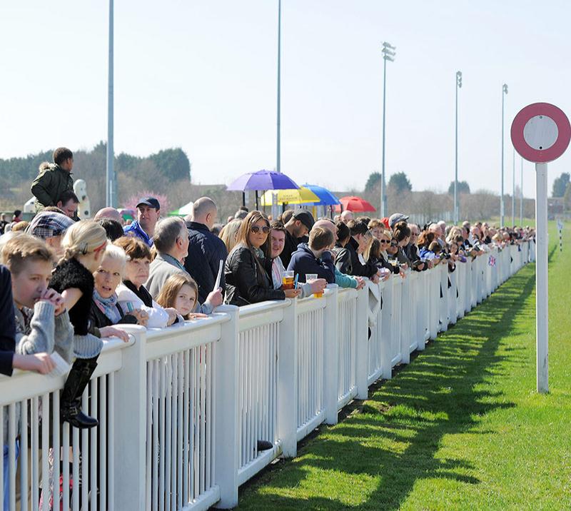Crowds lined up against the track railing to watch the racing action up close.