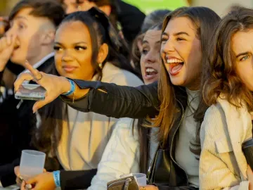 A racegoer laughs and points at the track at Wolverhampton Races