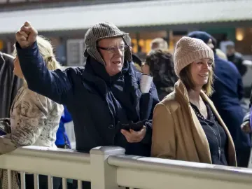 Two racegoers in winter hats watch the racing at Wolverhampton